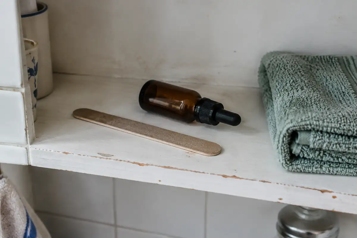 Lime en carton et flacon compte-gouttes ambré sur une étagère de salle de bain