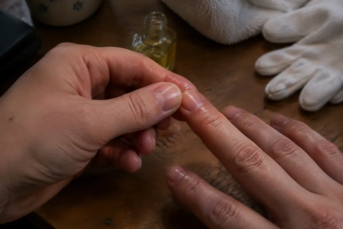 Pouce massant une fine couche d'huile sur la cuticule et l'ongle de l'index
